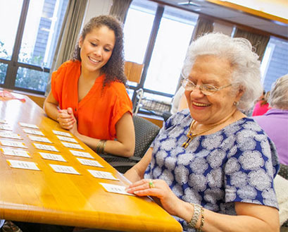 A Ƶ nursing student plays cards with an elderly community member