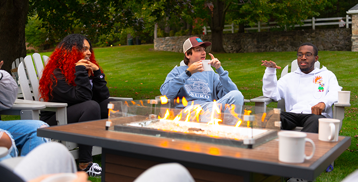 Ƶ Student Admission tour guides converse and have hot cocoa at the firepit on campus.
